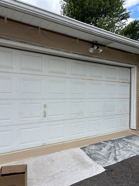 Worn and rust-stained metal garage door before sanding and painting in Crystal, MN