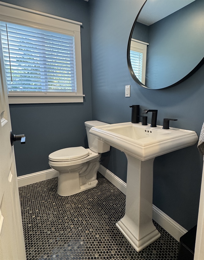 Completed Minnetonka bathroom remodel with pedestal sink, porcelain penny tile floor, blue walls, and updated fixtures
