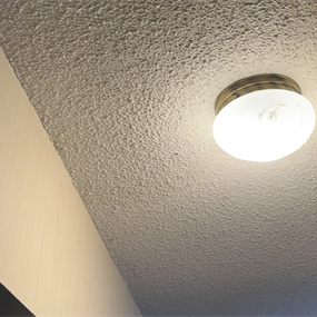 Completed popcorn ceiling repair with matched texture around a ceiling light