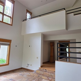 Completed Lake Elmo interior painting project with vaulted ceilings, tall windows, and refinished black railings