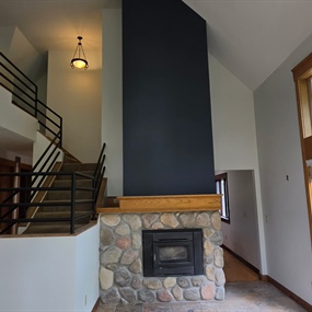 Two-story stone fireplace with black accent wall and refinished metal stair railings