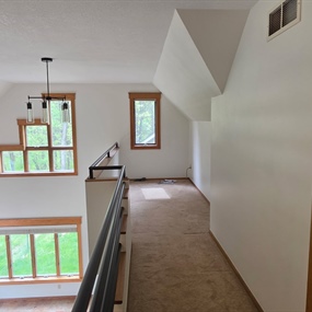 Upstairs landing with painted walls, vaulted knockdown ceiling texture, and black metal railing