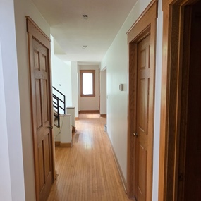 Freshly painted upstairs hallway with hardwood floors and natural wood trim