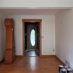 Painted front entry interior with white walls, hardwood flooring, and original wood trim