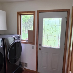 Freshly painted laundry room with washer, dryer, exterior door, and natural wood trim