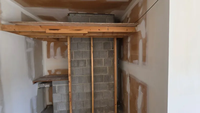 Exposed block fireplace chase and patched drywall in an Apple Valley garage before repair