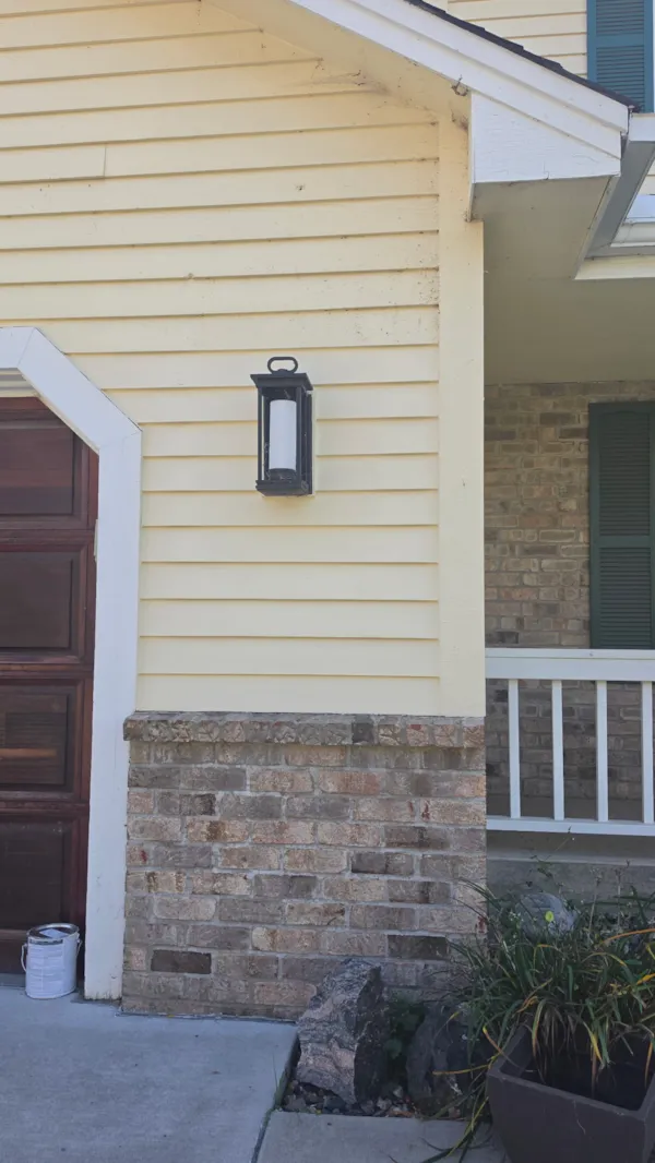 Repaired Burnsville siding painted to match the existing yellow exterior beside the garage