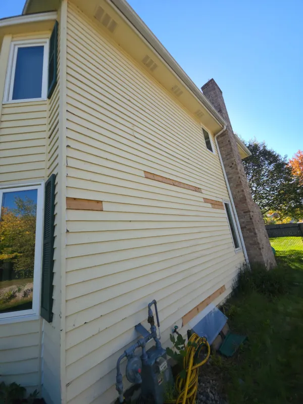 Side wall of a Burnsville home with raw wood siding patches replacing rotted boards