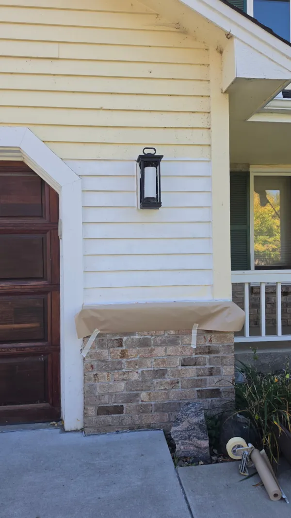 Replacement wood siding primed white with the brick ledge masked off during exterior repair