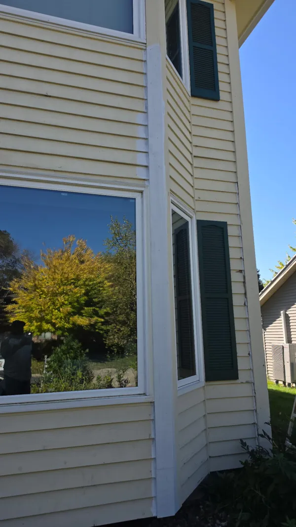 Bay window trim and surrounding siding primed white during exterior wood repair